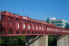 A group of women stand along a red bridge labeled Indiana University South Bend.
